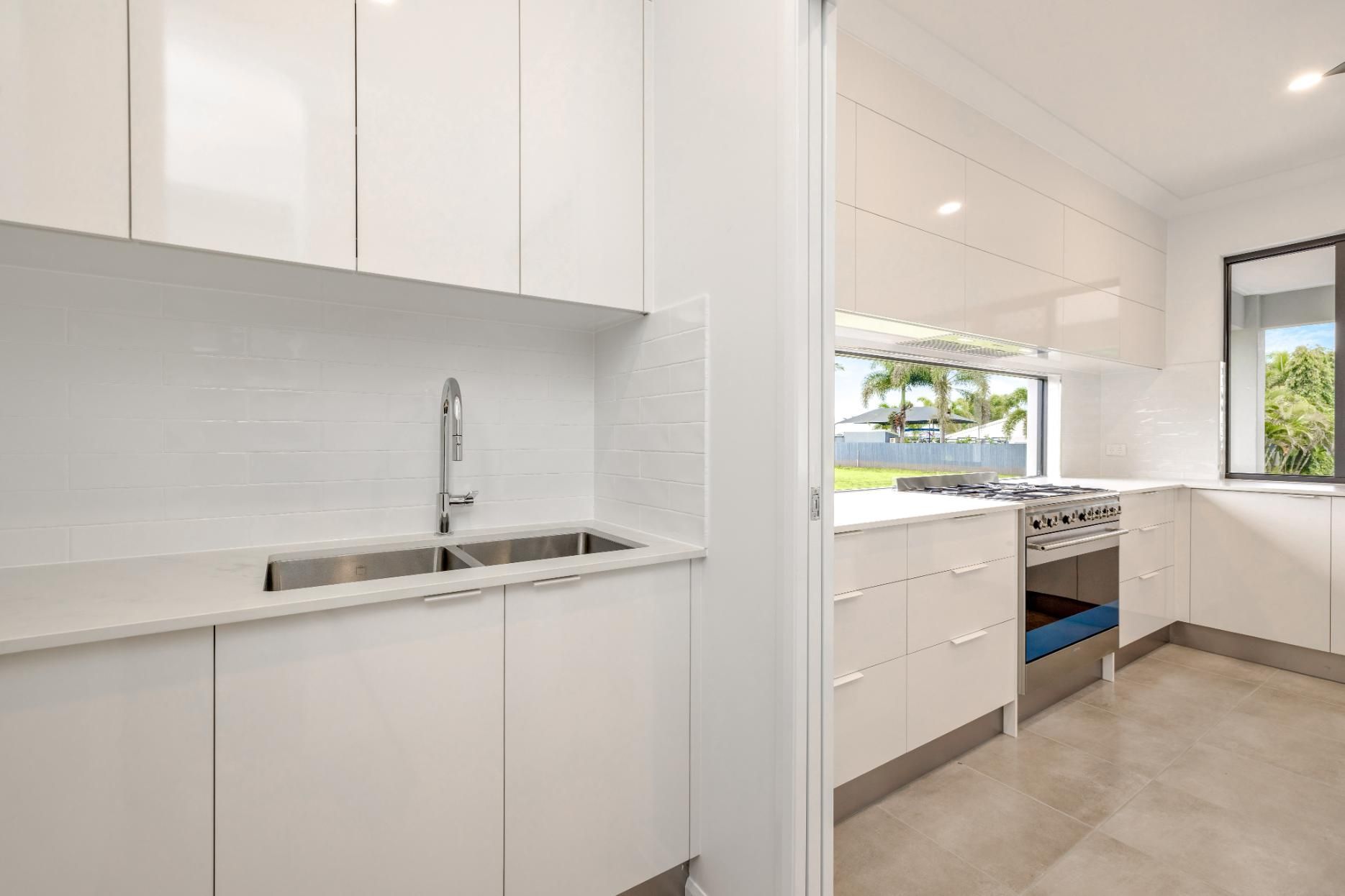 A Kitchen With White Cabinets, a Sink, a Stove and a Window — Ashlee Jones Homes in Gordonvale, QLD