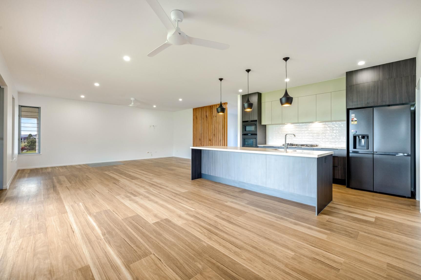 An Empty Kitchen With Hardwood Floors and a Ceiling Fan — Ashlee Jones Homes in Gordonvale, QLD