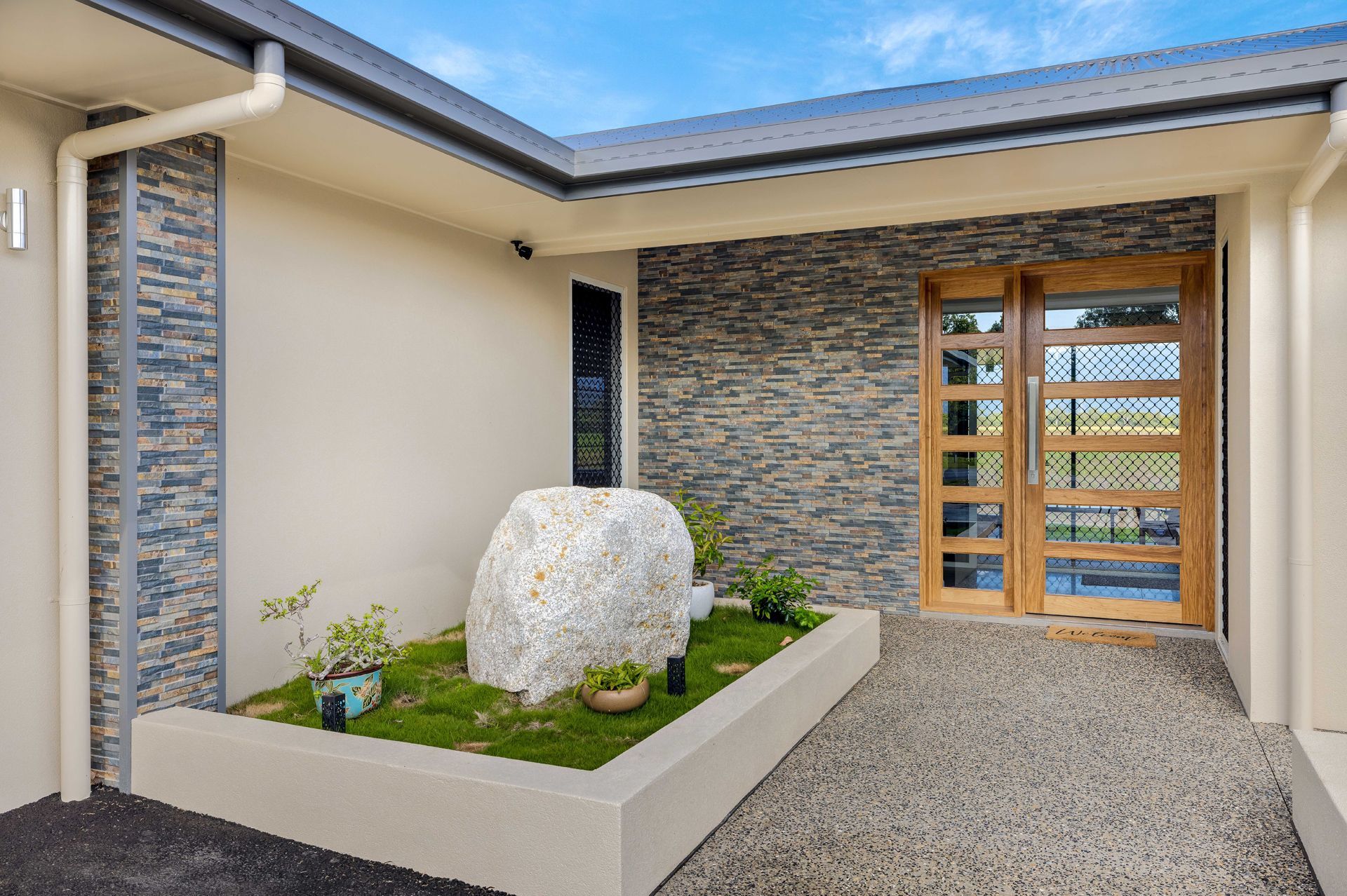 A House Entryway Featuring a Raised Garden Bed With a Large Stone — Ashlee Jones Homes in Gordonvale, QLD