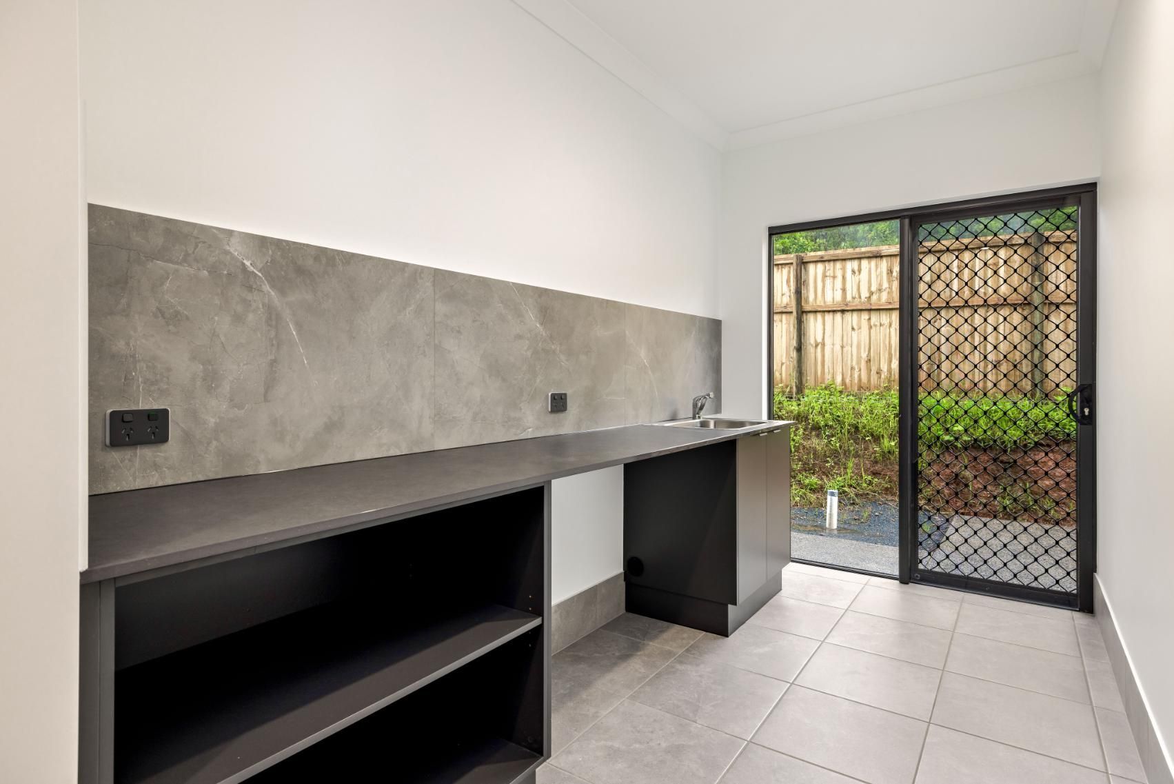 A Kitchen With a Sliding Glass Door and a Sink — Ashlee Jones Homes in Gordonvale, QLD