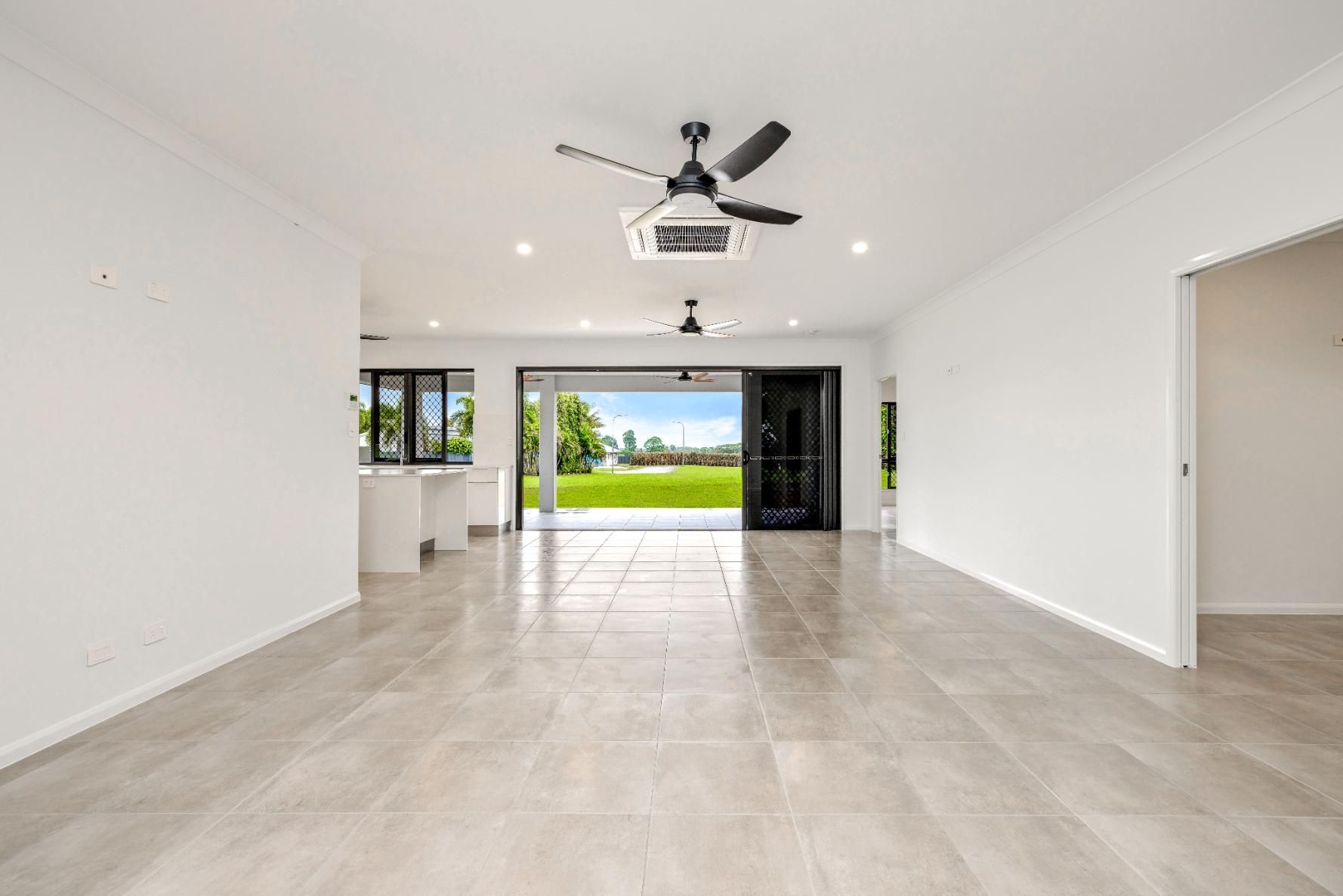 An Empty Living Room With a Ceiling Fan and Sliding Glass Doors — Ashlee Jones Homes in Gordonvale, QLD