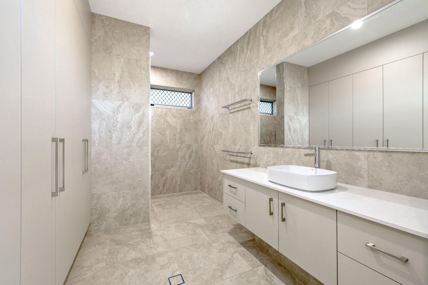 A Bathroom With a Sink, Mirror and Walk in Shower — Ashlee Jones Homes in Gordonvale, QLD