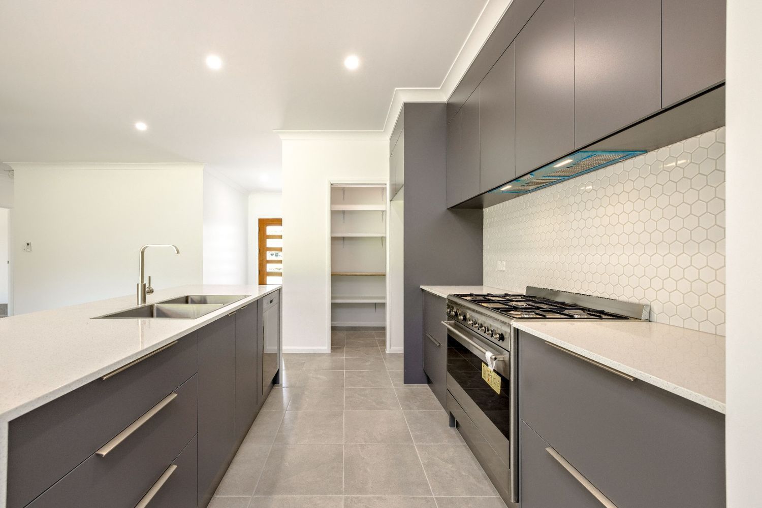 A Kitchen With Gray Cabinets, White Counter Tops, a Stove and a Sink — Ashlee Jones Homes in Gordonvale, QLD
