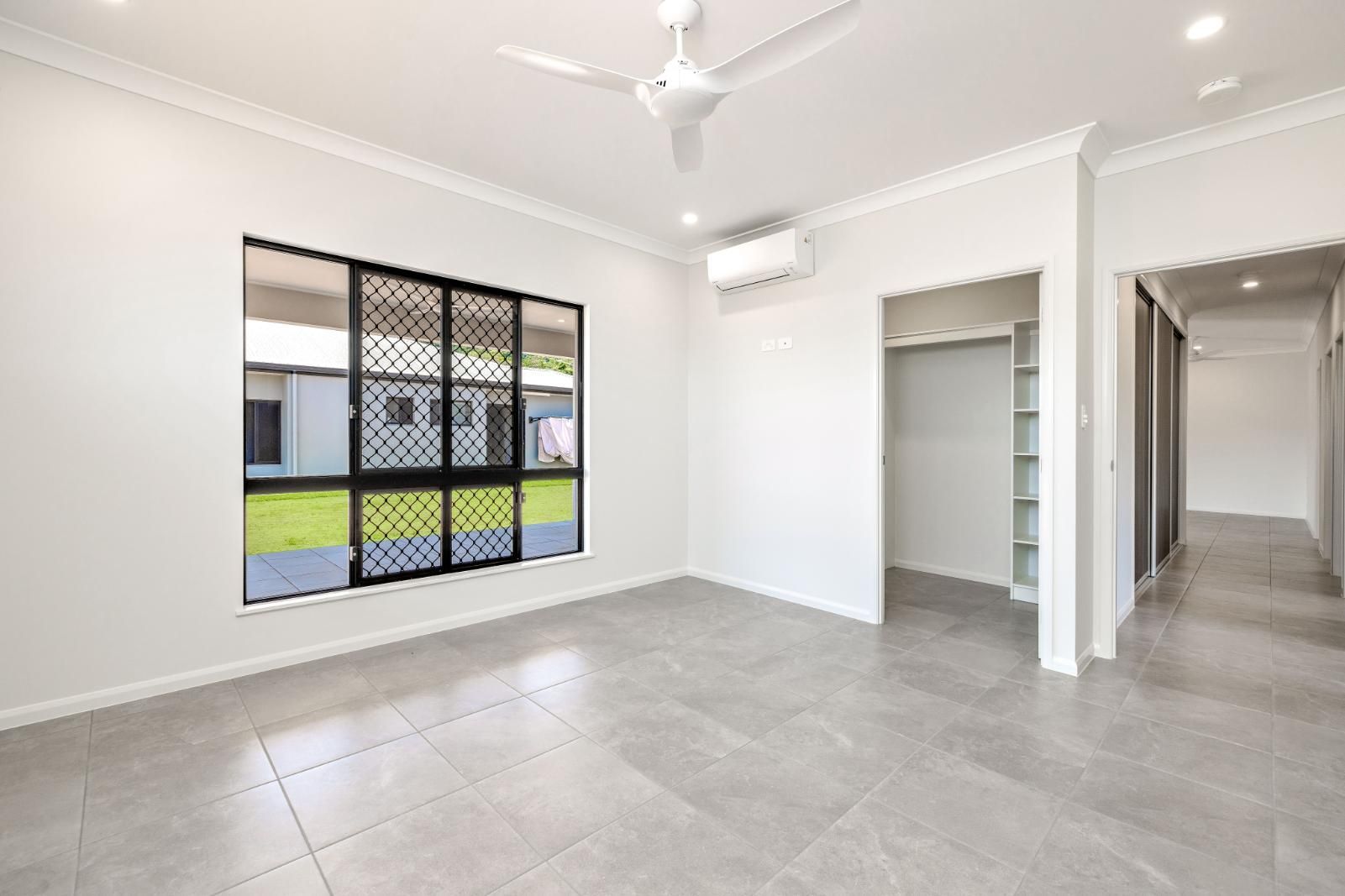 An Empty Living Room With a Ceiling Fan and a Large Window — Ashlee Jones Homes in Gordonvale, QLD