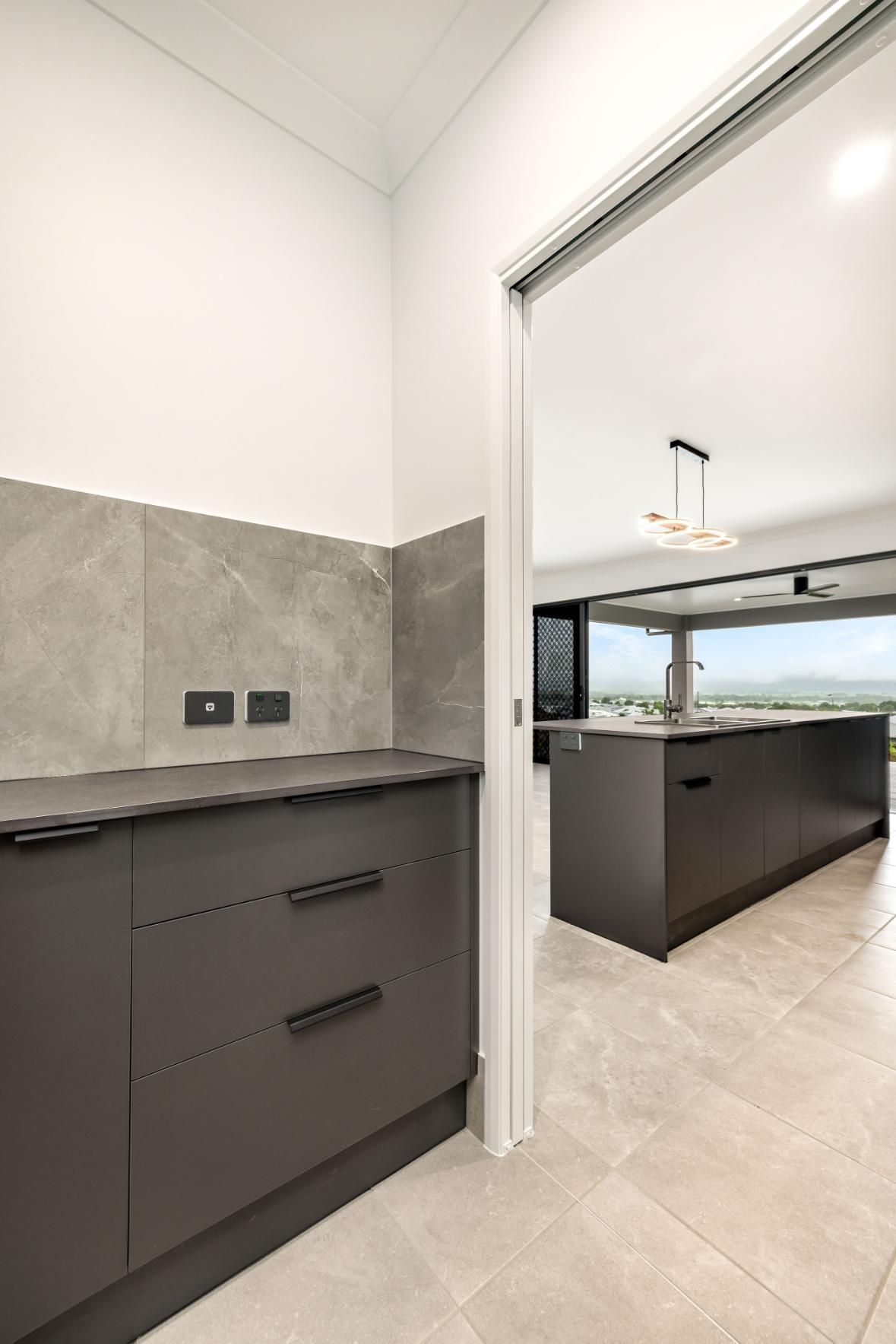 A Kitchen With Black Cabinets and a Large Island in the Middle of the Room — Ashlee Jones Homes in Gordonvale, QLD