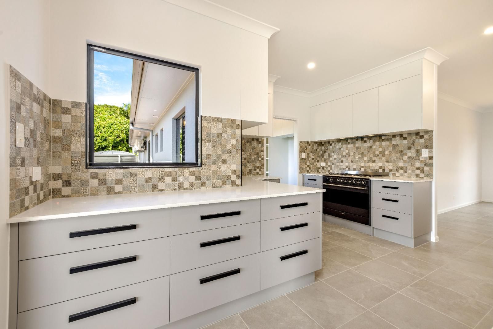 A Kitchen With White Cabinets, a Stove, and a Window — Ashlee Jones Homes in Gordonvale, QLD