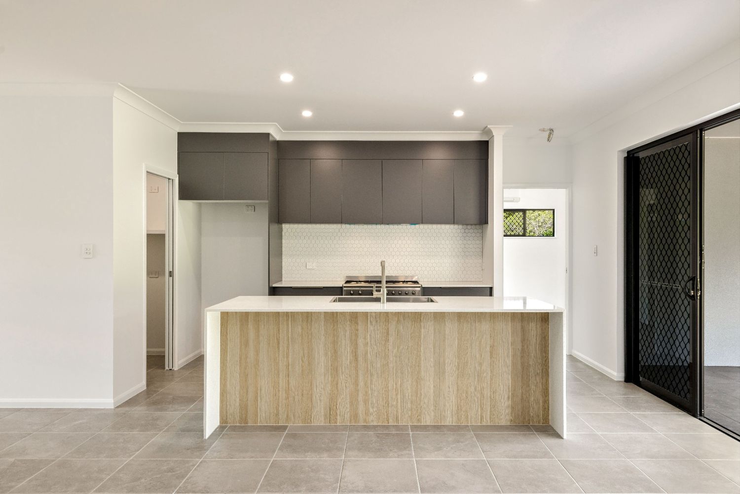 An Empty Kitchen With a Large Island in the Middle of the Room — Ashlee Jones Homes in Gordonvale, QLD