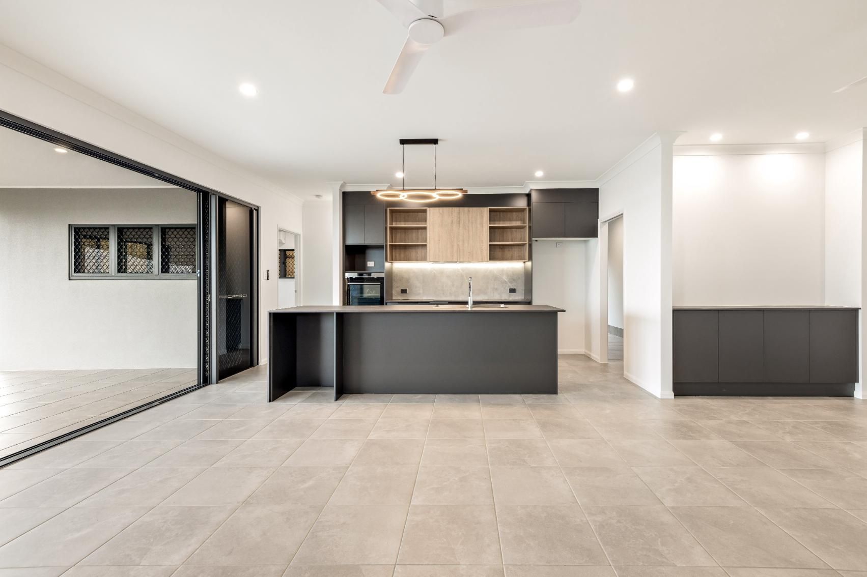 A Large Empty Room With a Kitchen and a Ceiling Fan — Ashlee Jones Homes in Gordonvale, QLD