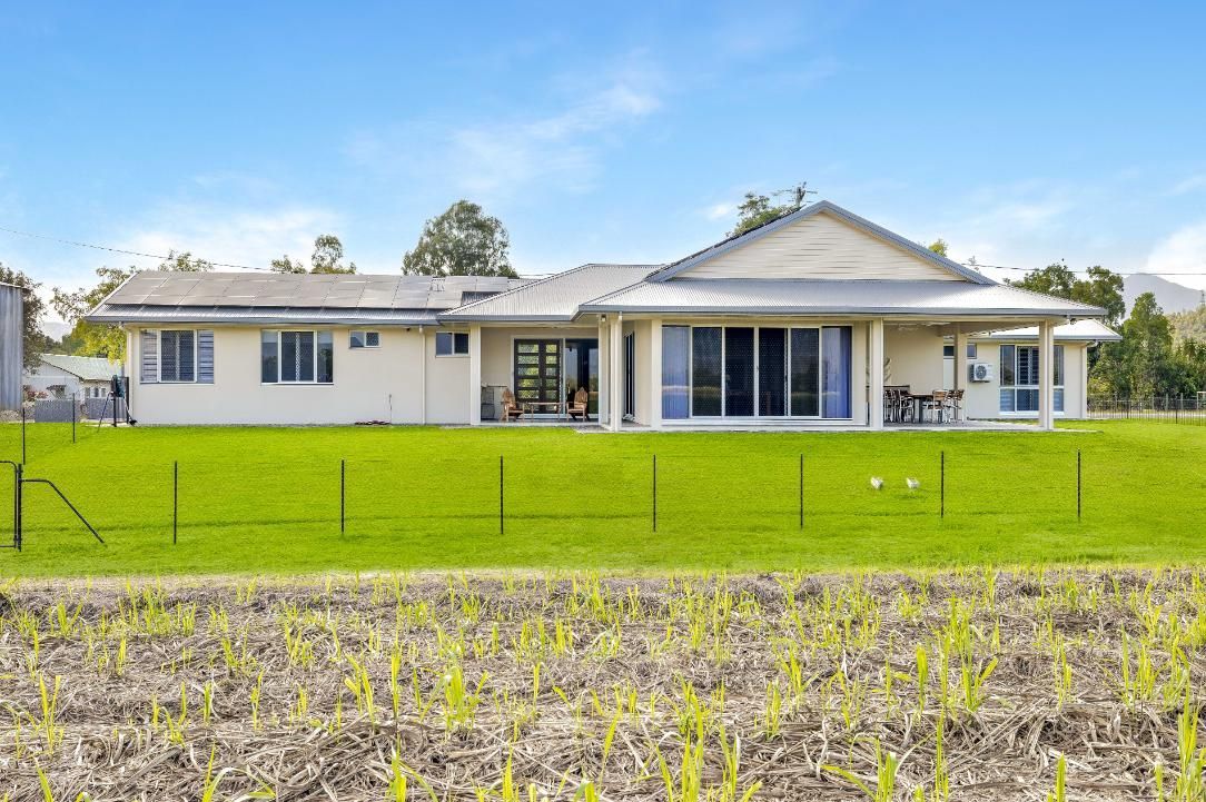 A Large White House is Sitting on Top of a Lush Green Field — Ashlee Jones Homes in Gordonvale, QLD