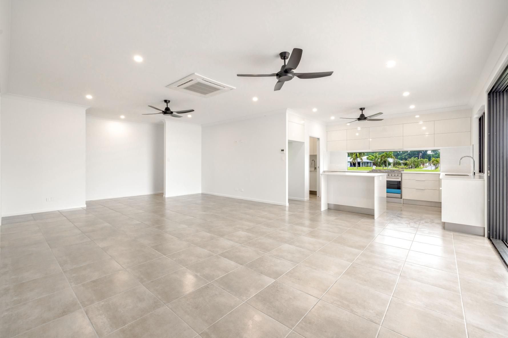 A Large Empty Room With Tile Floors and Ceiling Fans in a House — Ashlee Jones Homes in Gordonvale, QLD