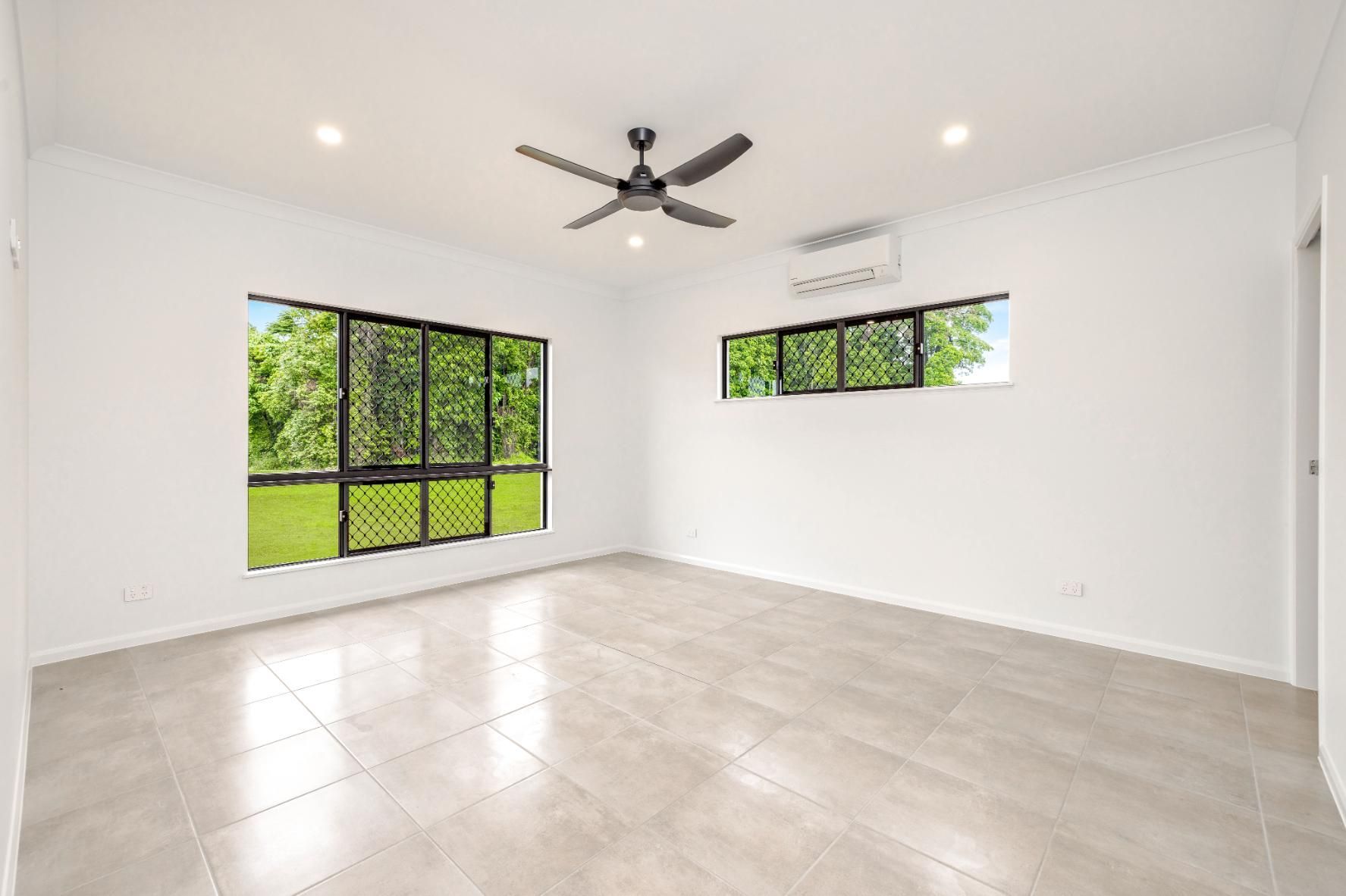 An Empty Room With a Ceiling Fan and Two Windows — Ashlee Jones Homes in Gordonvale, QLD