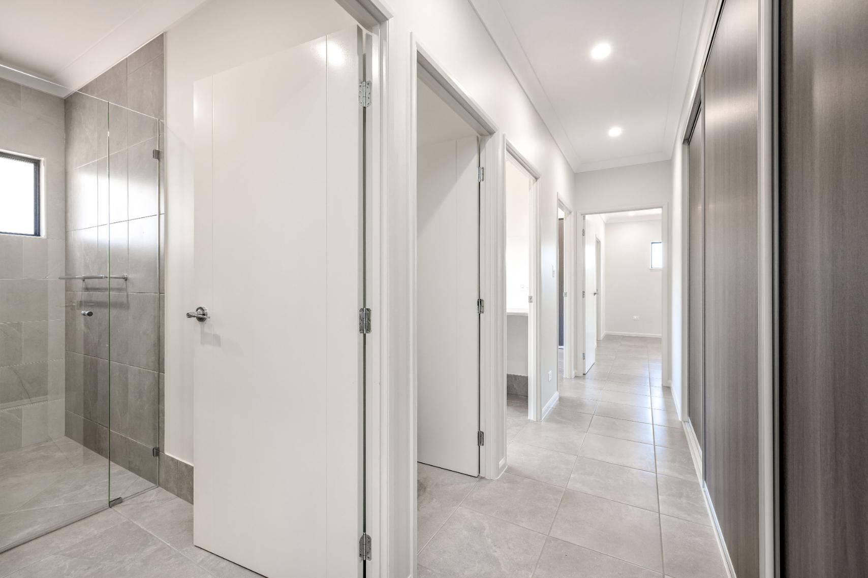 A Long Hallway in a House With White Doors and a Walk in Shower — Ashlee Jones Homes in Gordonvale, QLD