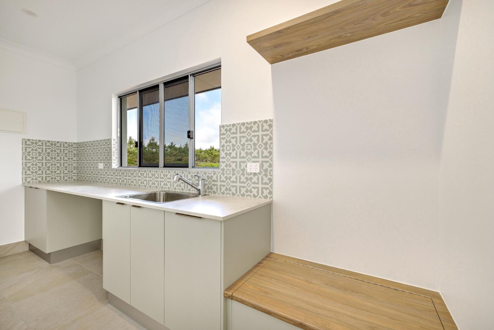 A Kitchen With White Cabinets, a Sink, and a Window — Ashlee Jones Homes in Gordonvale, QLD