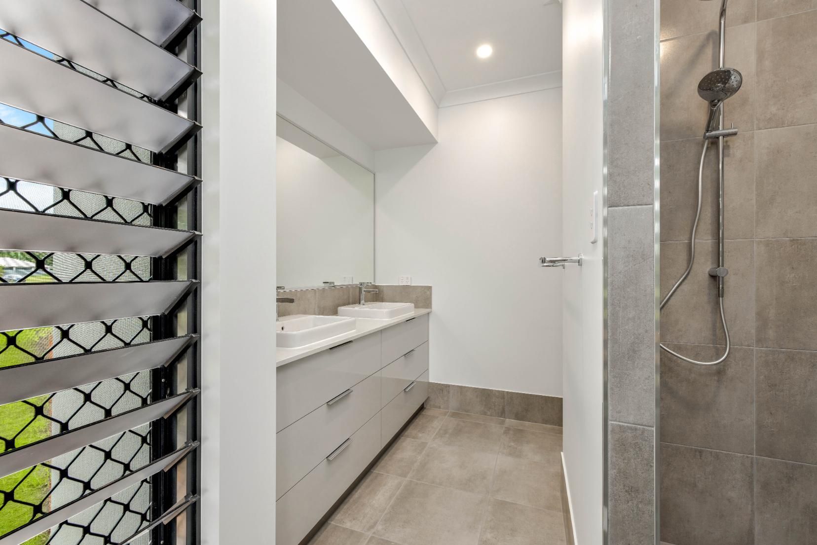 A Bathroom With Two Sinks and a Walk in Shower — Ashlee Jones Homes in Gordonvale, QLD