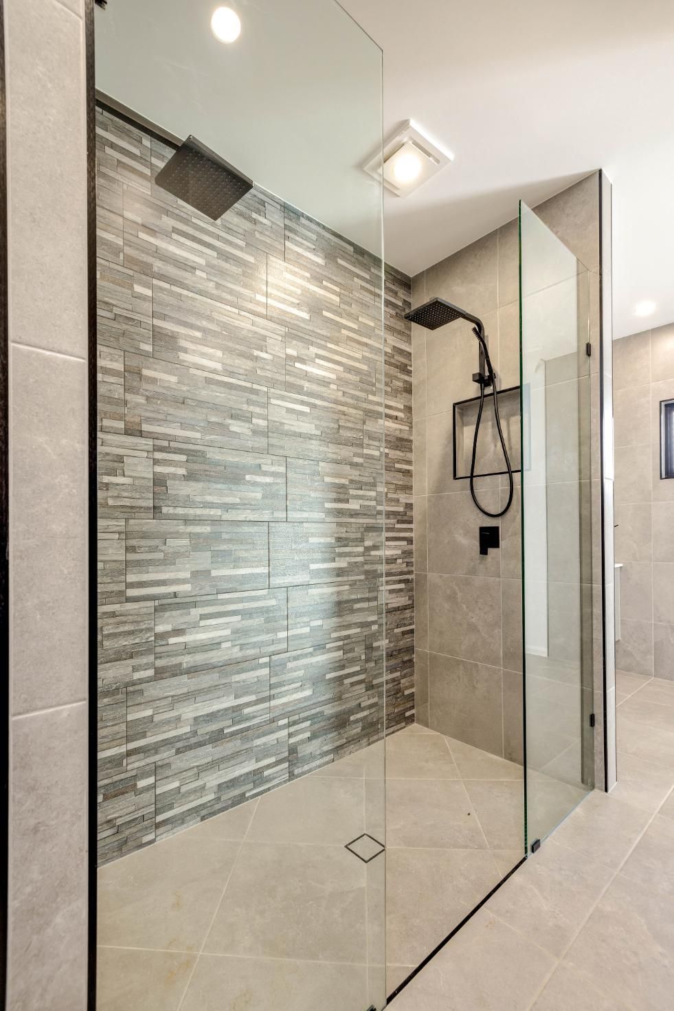 A Walk in Shower With a Tiled Wall and a Glass Door — Ashlee Jones Homes in Gordonvale, QLD