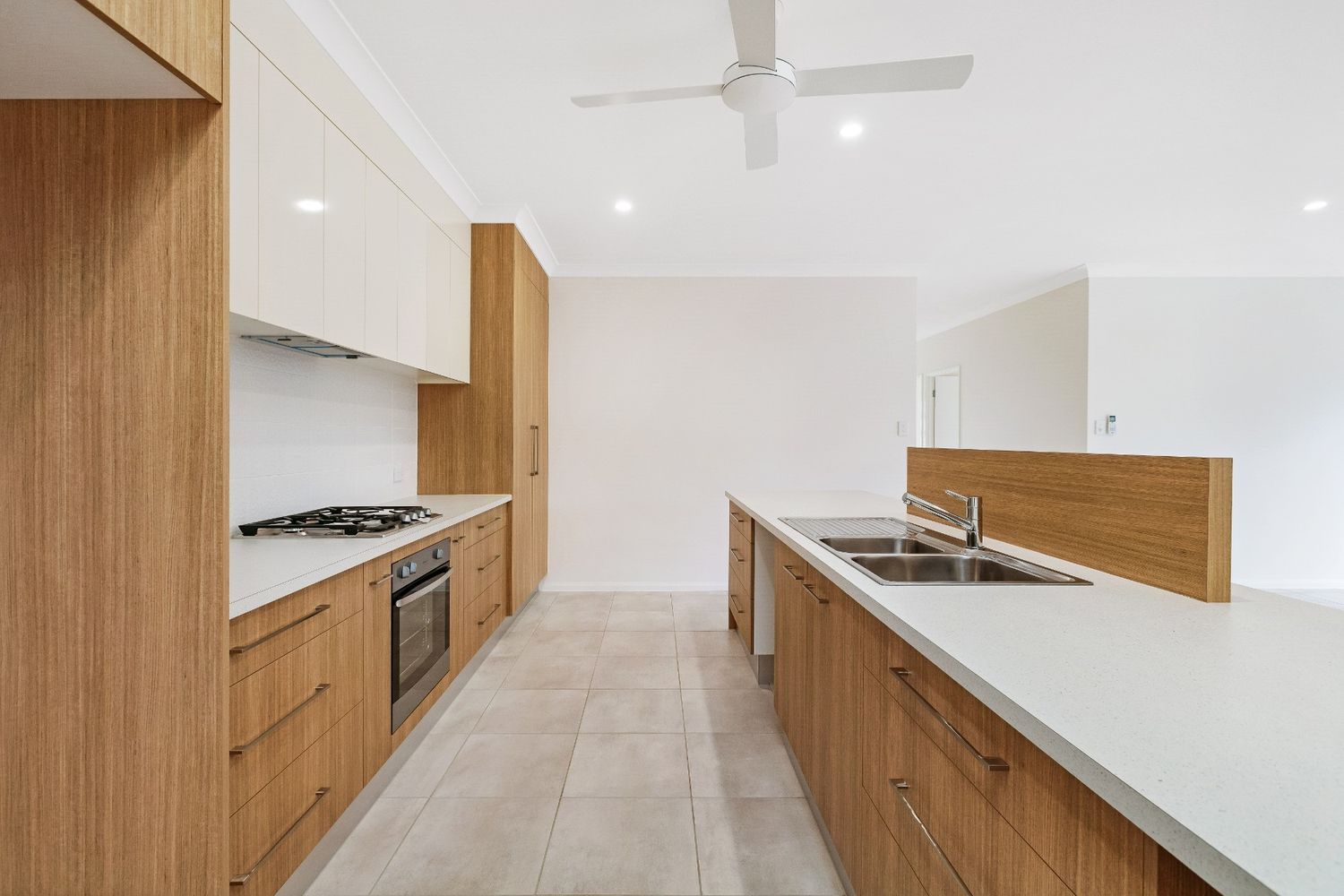 A Kitchen With Wooden Cabinets and White Counter Tops and a Ceiling Fan — Ashlee Jones Homes in Gordonvale, QLD