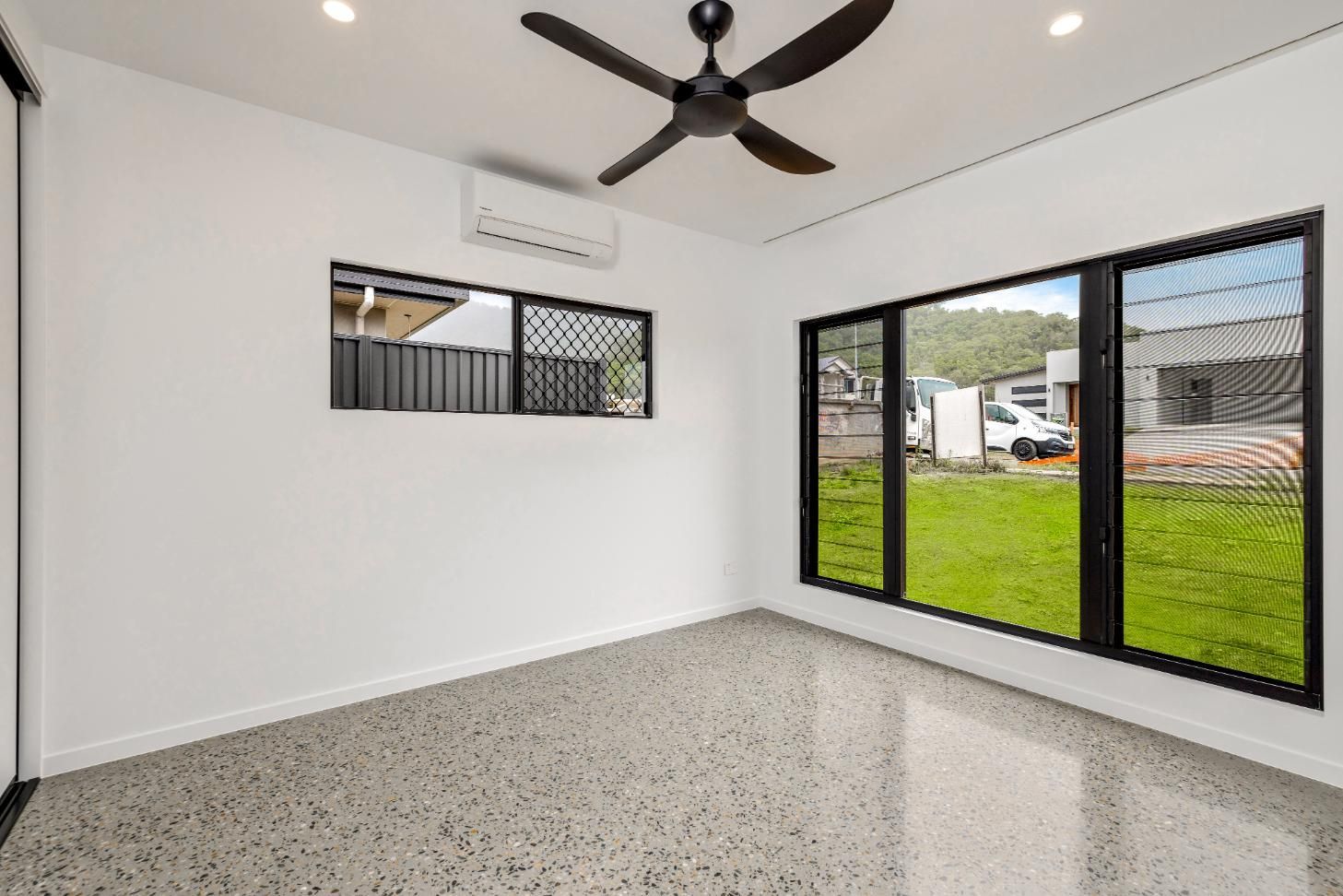 An Empty Room with A Ceiling Fan and A Lot of Windows — Ashlee Jones Homes in Gordonvale, QLD