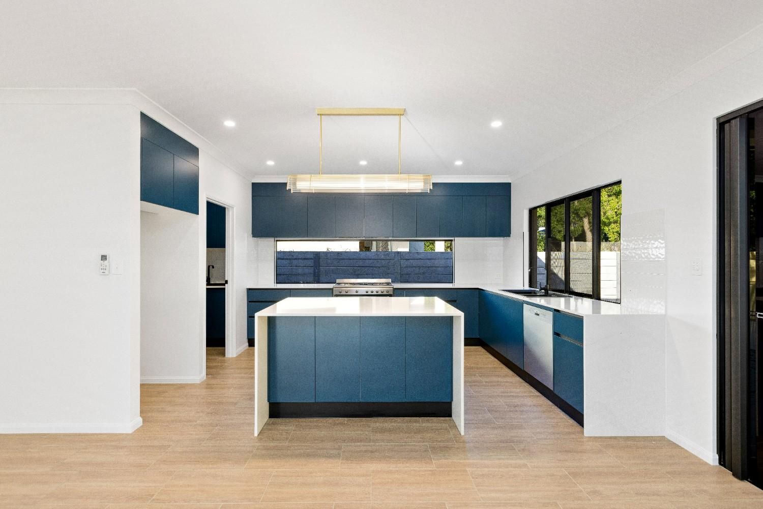 A Kitchen With White Cabinets, a Sink, a Stove and a Window — Ashlee Jones Homes in Gordonvale, QLD