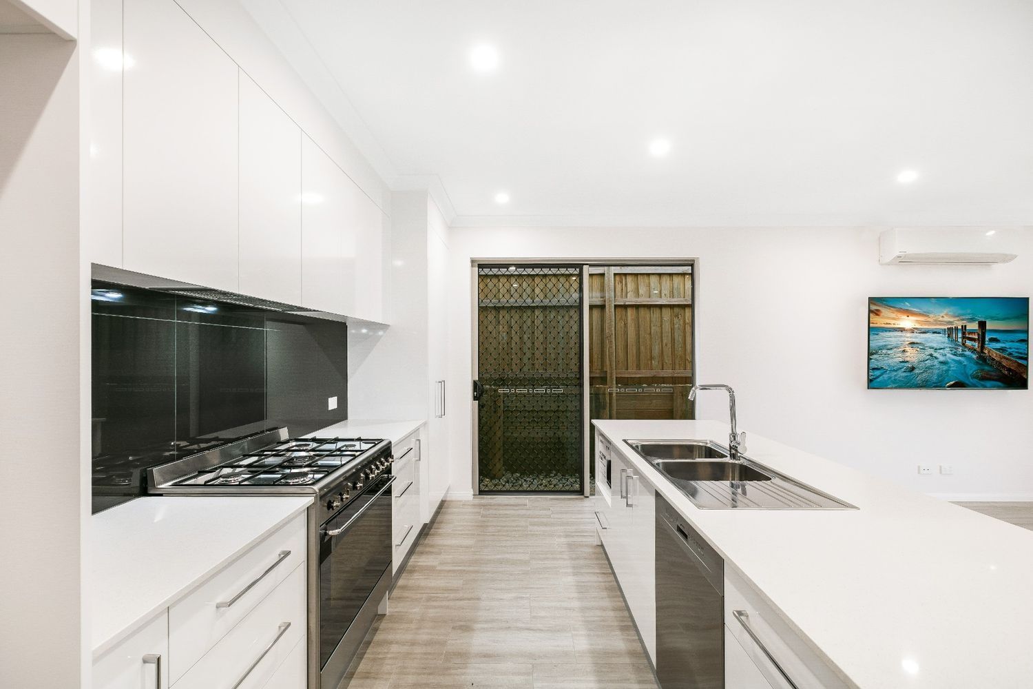 A Kitchen With White Cabinets and Stainless Steel Appliances and a Picture on the Wall — Ashlee Jones Homes in Gordonvale, QLD