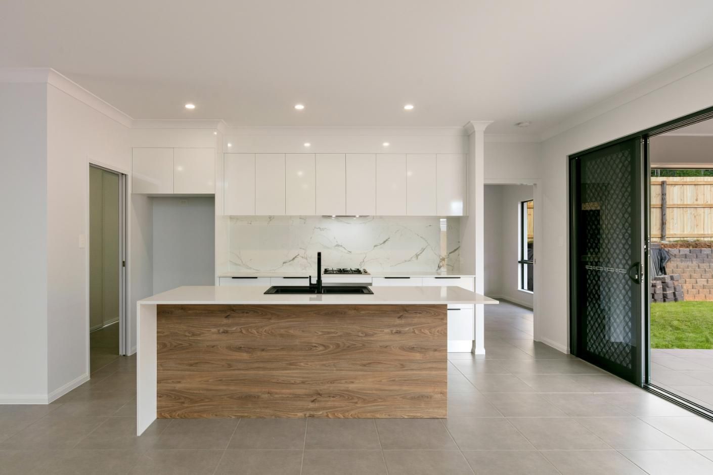 An Empty Kitchen With White Cabinets and a Wooden Island — Ashlee Jones Homes in Gordonvale, QLD