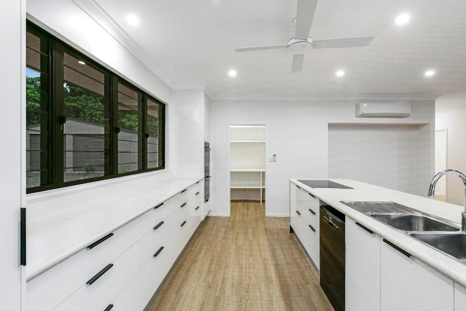 A Kitchen With White Cabinets and a Ceiling Fan — Ashlee Jones Homes in Gordonvale, QLD