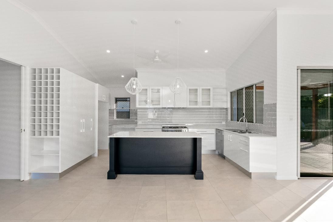 A Kitchen With White Cabinets and a Black Island — Ashlee Jones Homes in Gordonvale, QLD