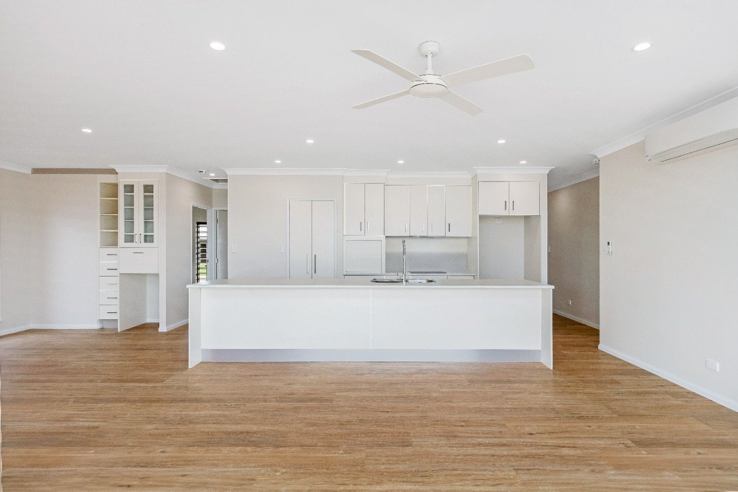 An Empty Kitchen With White Cabinets and a Ceiling Fan — Ashlee Jones Homes in Gordonvale, QLD