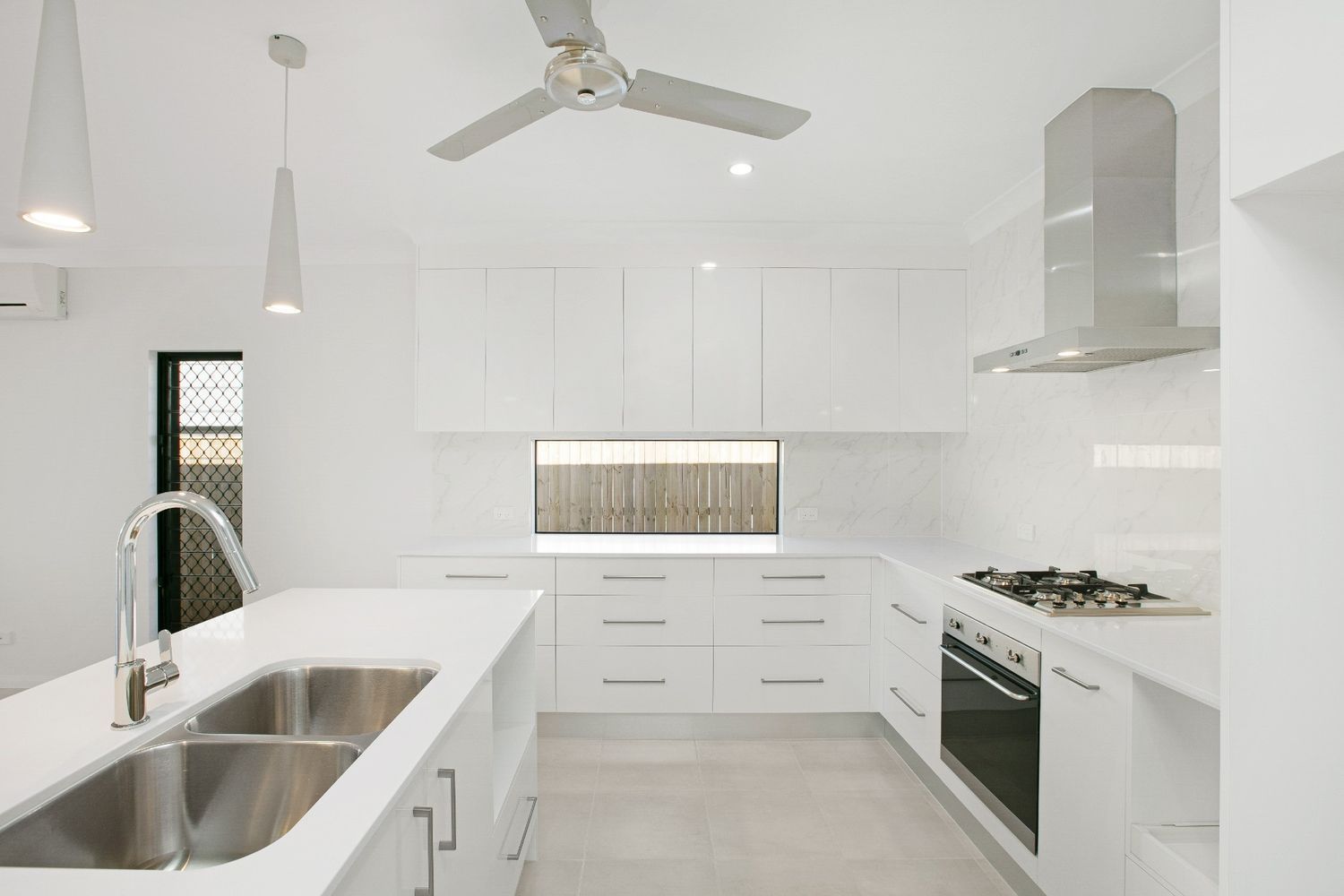 A Kitchen With White Cabinets and Stainless Steel Appliances — Ashlee Jones Homes in Gordonvale, QLD