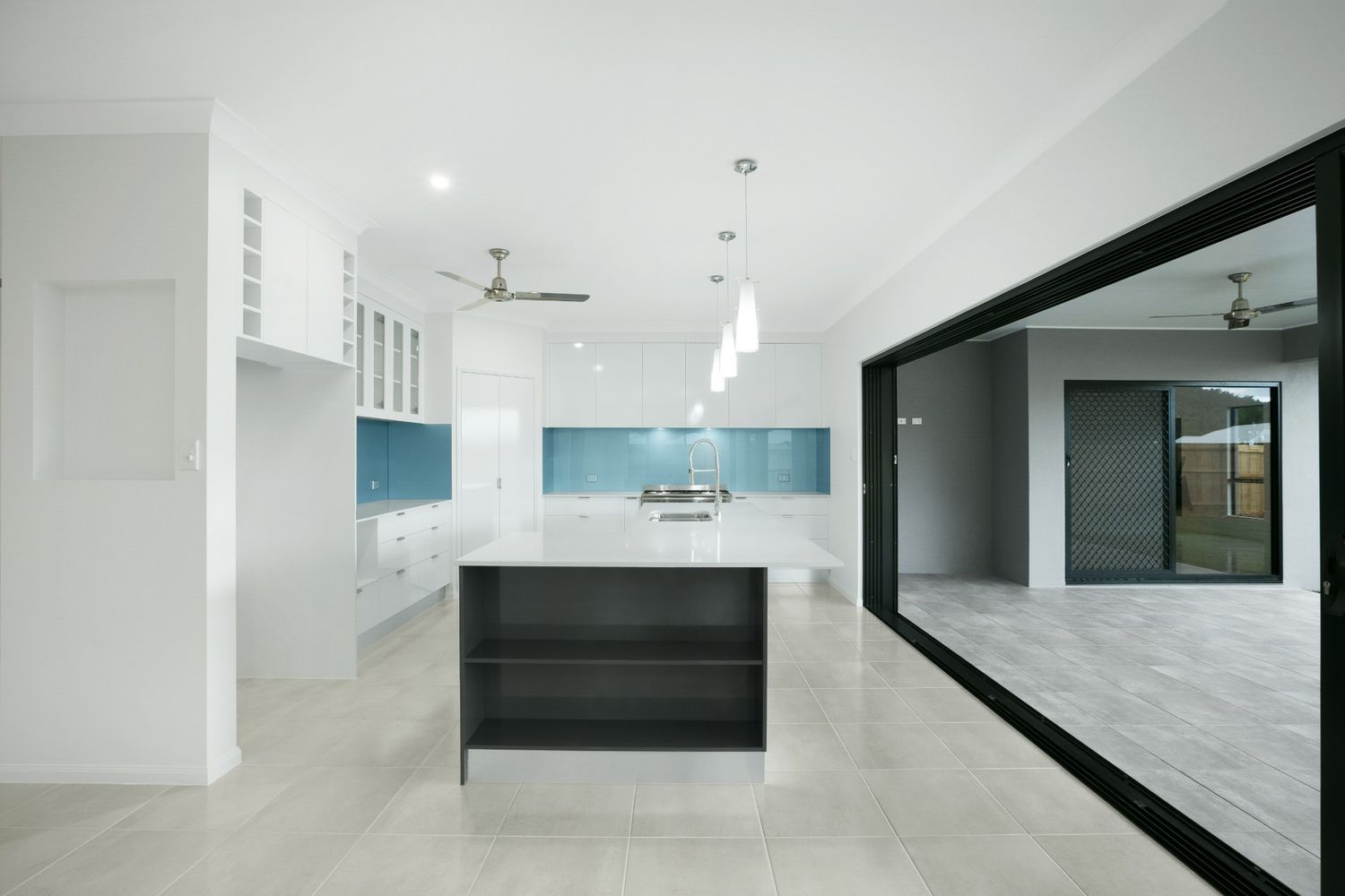 A Kitchen With a Large Island and Sliding Glass Doors — Ashlee Jones Homes in Gordonvale, QLD