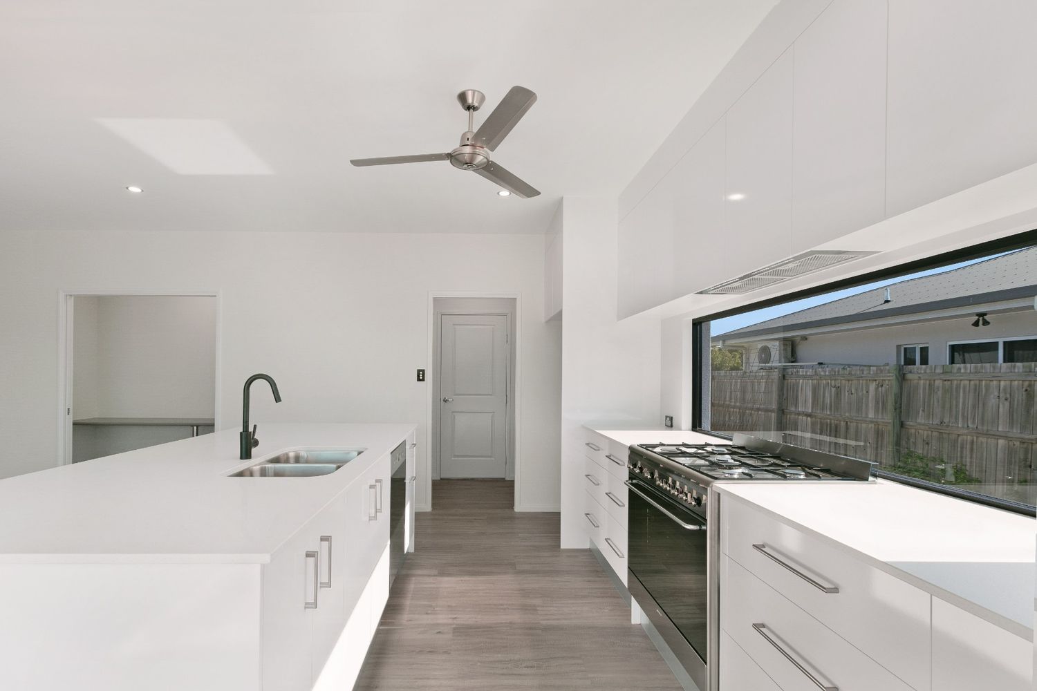 A Kitchen With White Cabinets and a Ceiling Fan — Ashlee Jones Homes in Gordonvale, QLD