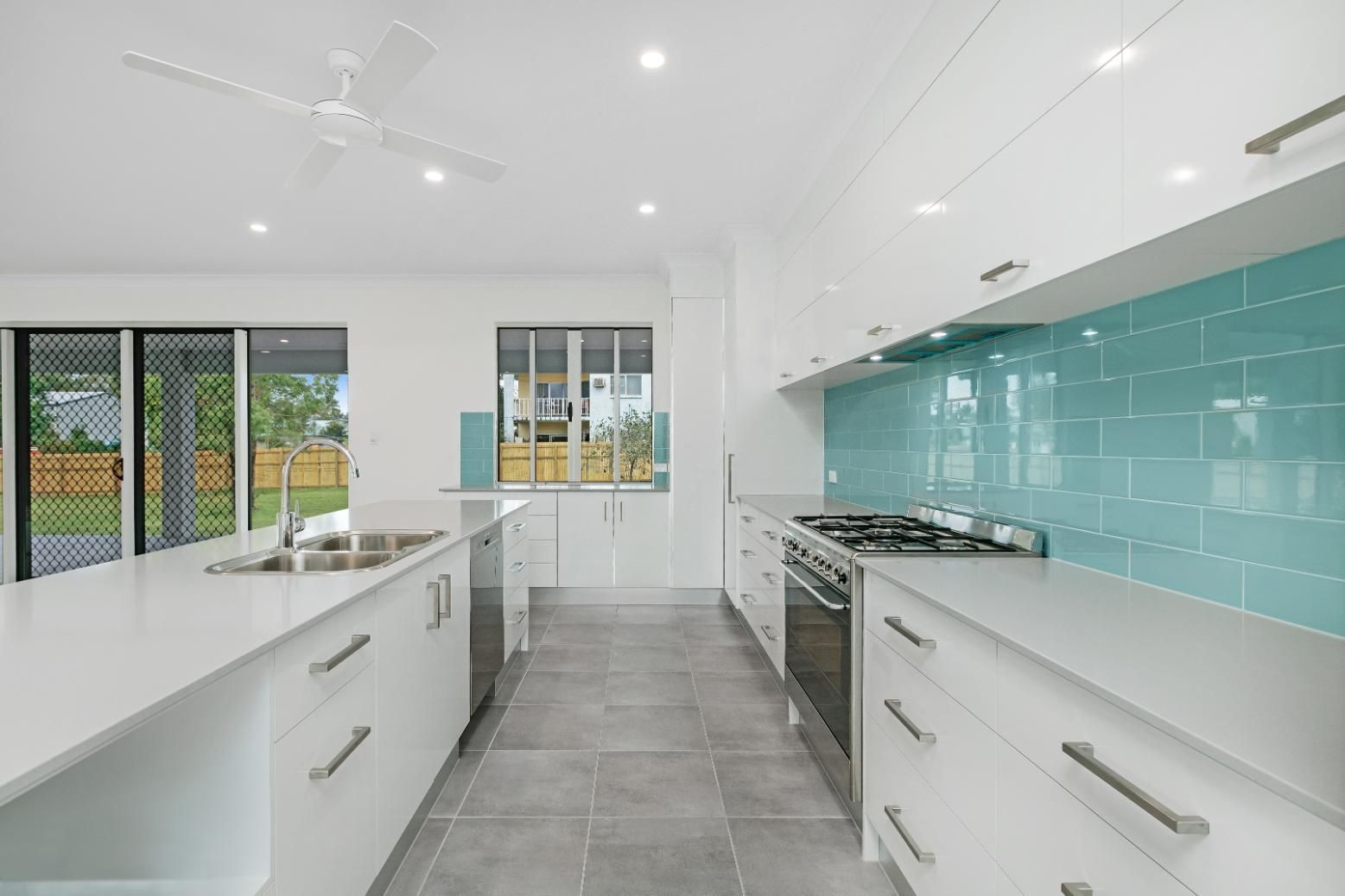 A Kitchen With White Cabinets and Blue Tiles — Ashlee Jones Homes in Gordonvale, QLD