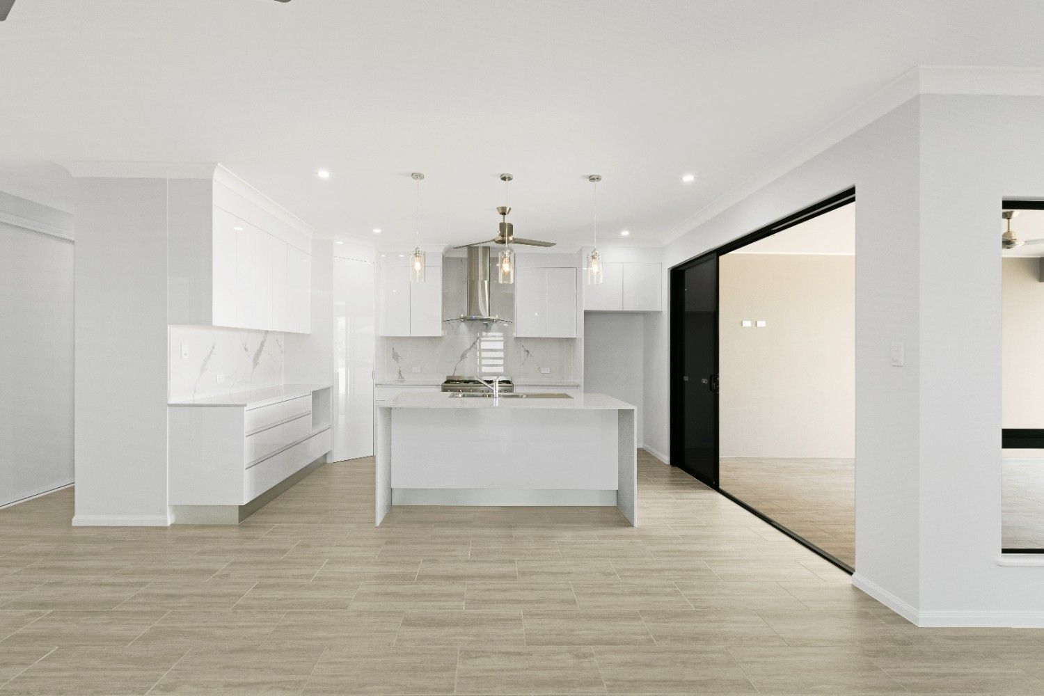 A Kitchen With White Cabinets and a Large Island in the Middle of the Room — Ashlee Jones Homes in Gordonvale, QLD