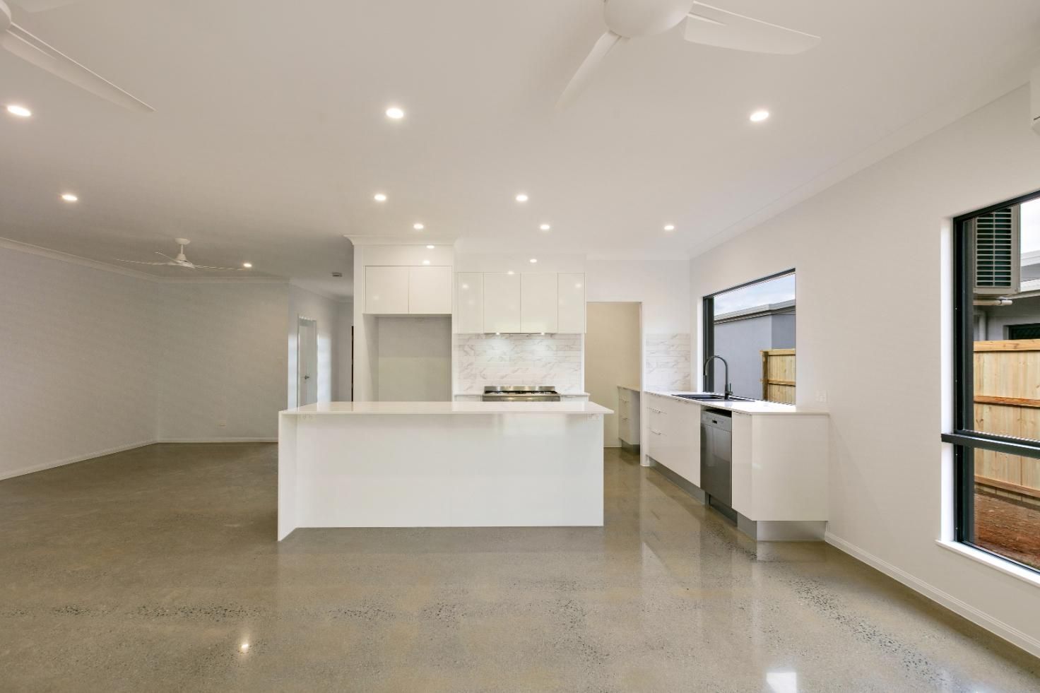 An Empty Kitchen With White Cabinets and a Ceiling Fan — Ashlee Jones Homes in Gordonvale, QLD