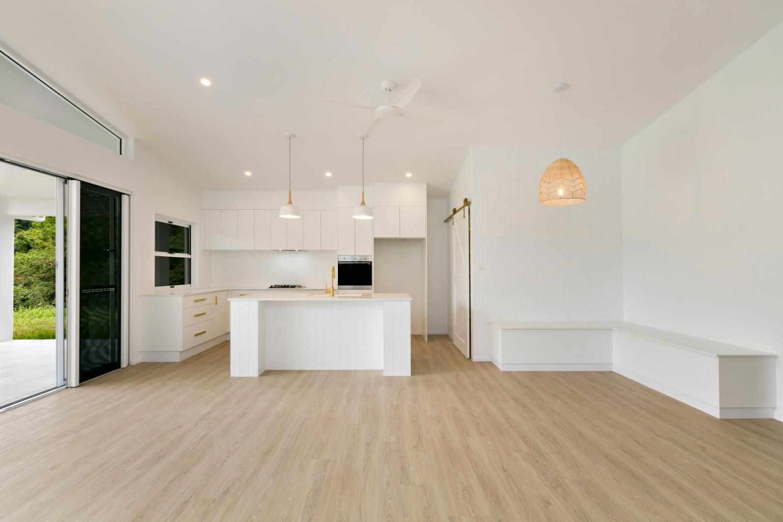 A Kitchen With White Cabinets and Wooden Floors in an Empty House — Ashlee Jones Homes in Gordonvale, QLD