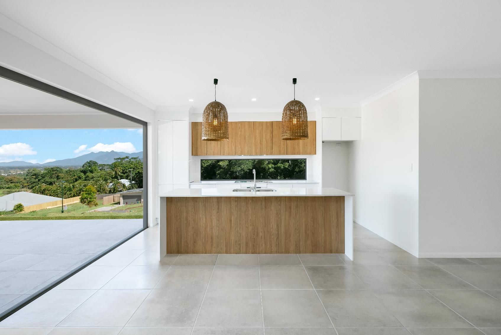 An Empty Kitchen With a Large Island and Sliding Glass Doors — Ashlee Jones Homes in Gordonvale, QLD