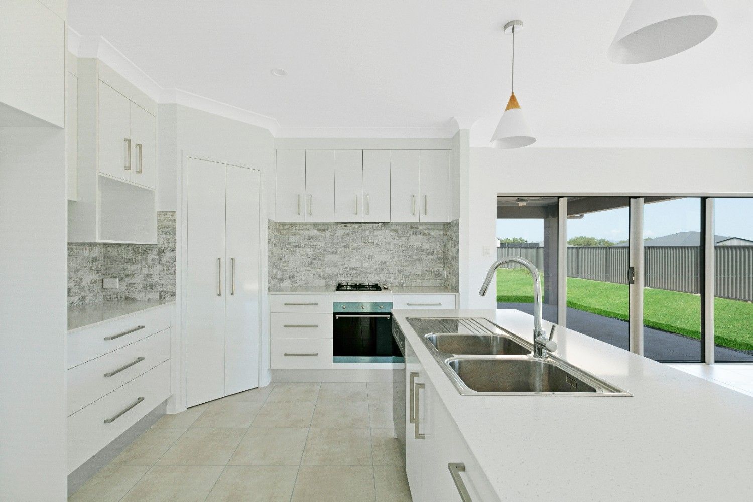 A Kitchen With White Cabinets and a Stainless Steel Sink — Ashlee Jones Homes in Gordonvale, QLD