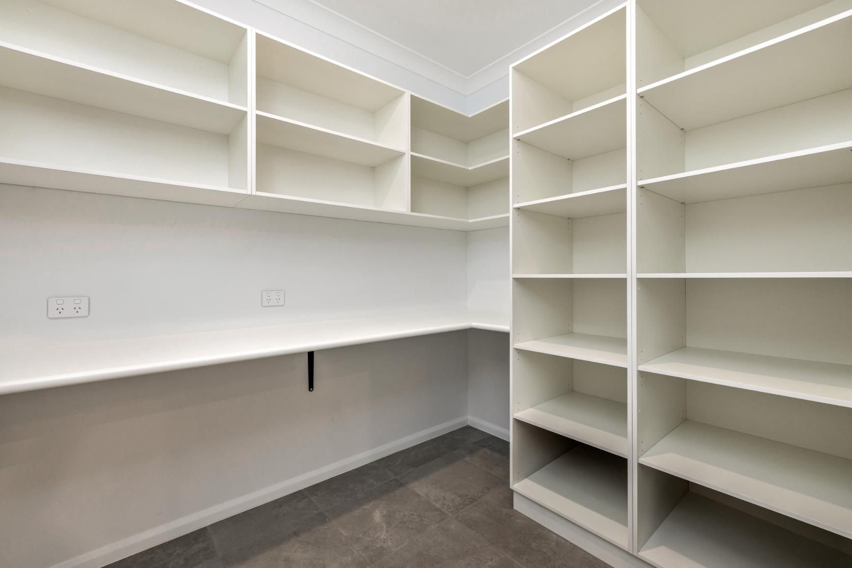 An Empty Walk in Closet With Lots of Shelves and a Desk — Ashlee Jones Homes in Gordonvale, QLD