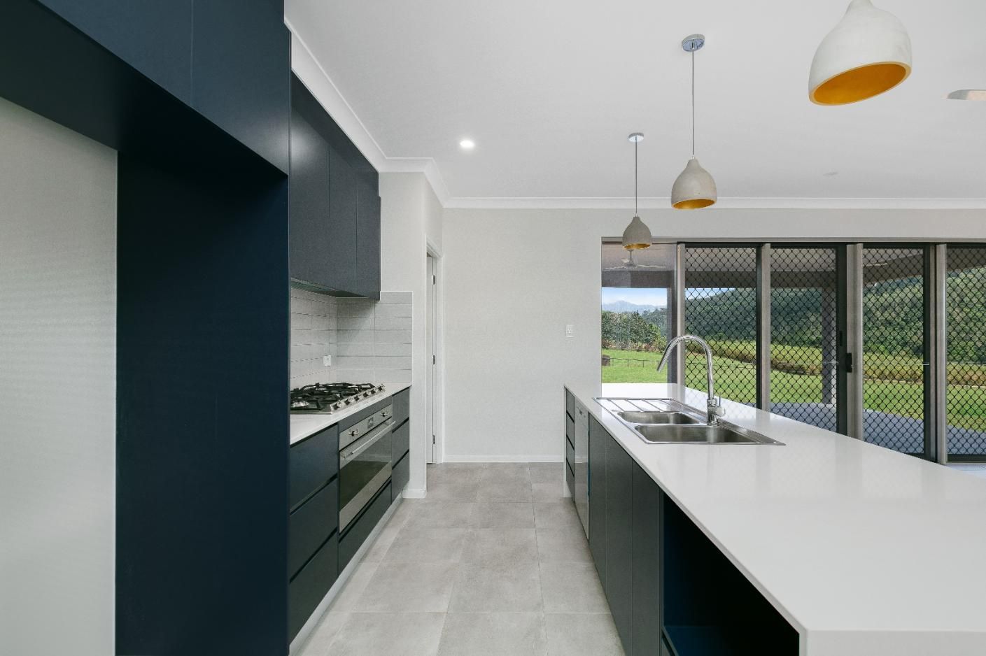 A Kitchen With Blue Cabinets and White Counter Tops — Ashlee Jones Homes in Gordonvale, QLD