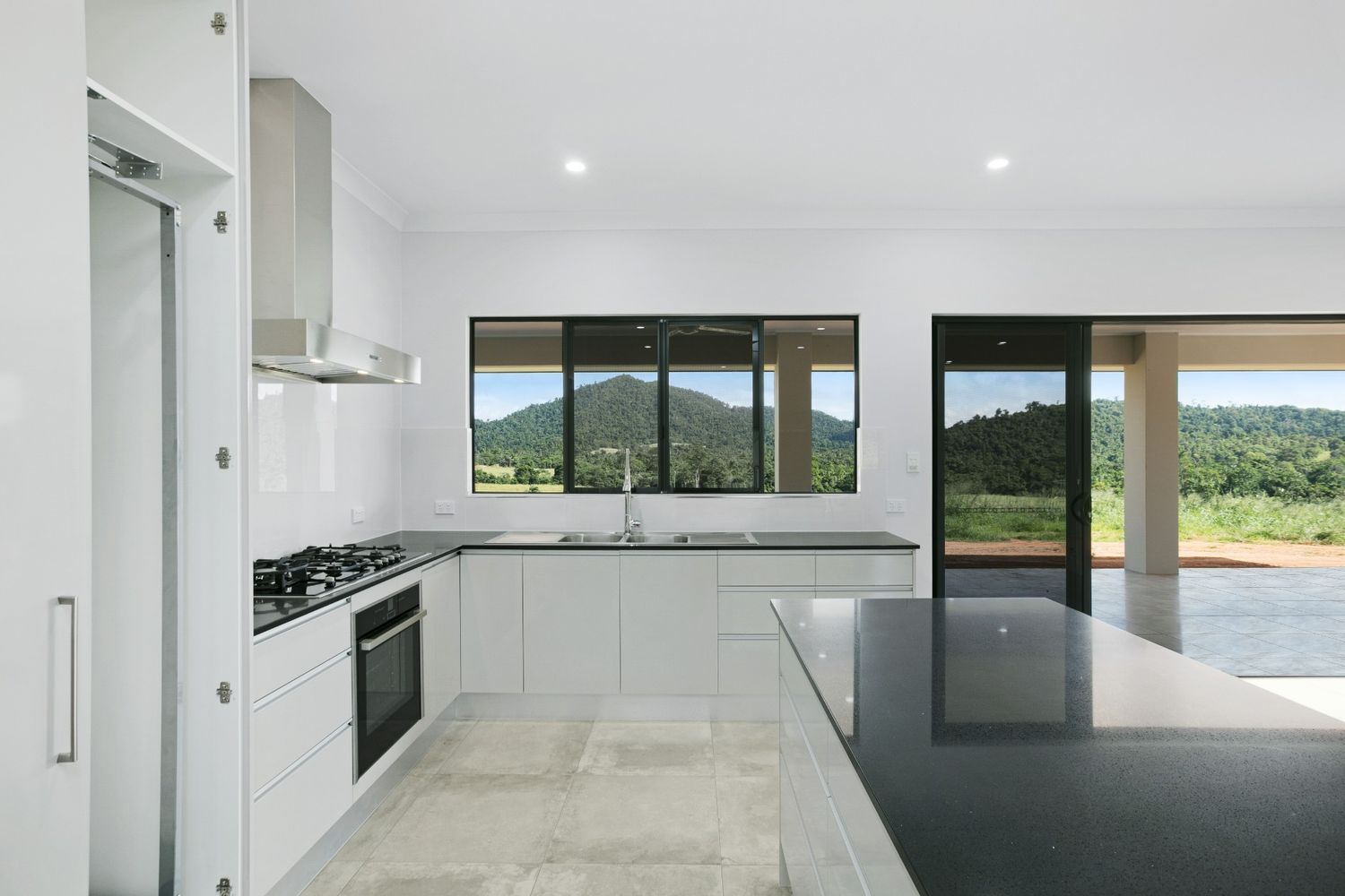 A Kitchen With White Cabinets and a Black Counter Top — Ashlee Jones Homes in Gordonvale, QLD
