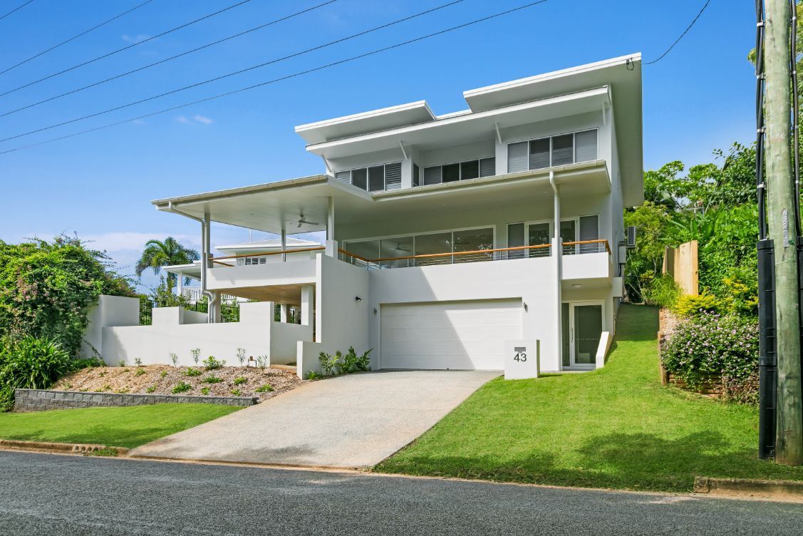 A Large White House is Sitting on Top of a Lush Green Hillside — Ashlee Jones Homes in Gordonvale, QLD