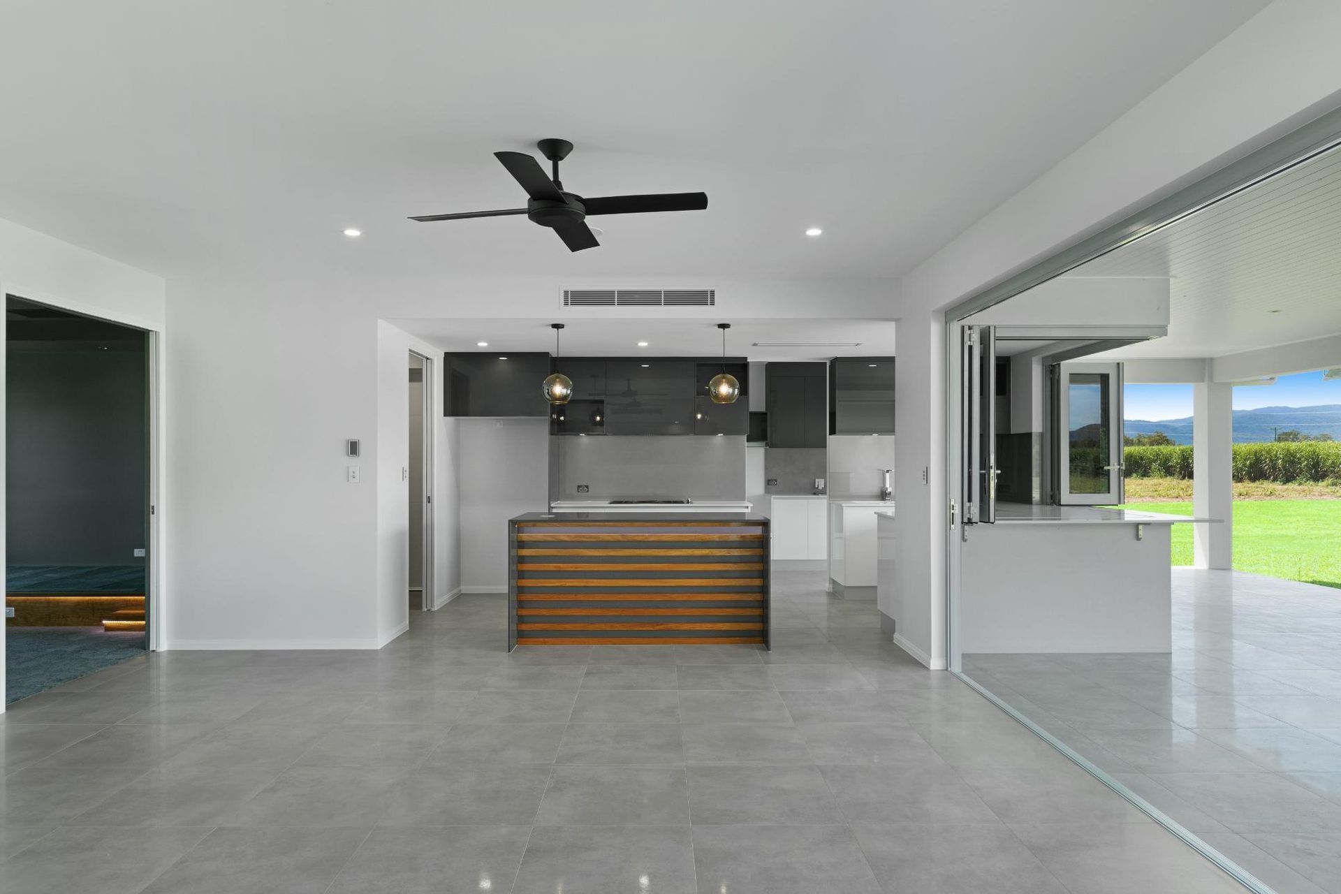 An Empty Kitchen With a Ceiling Fan and a Large Island — Ashlee Jones Homes in Gordonvale, QLD