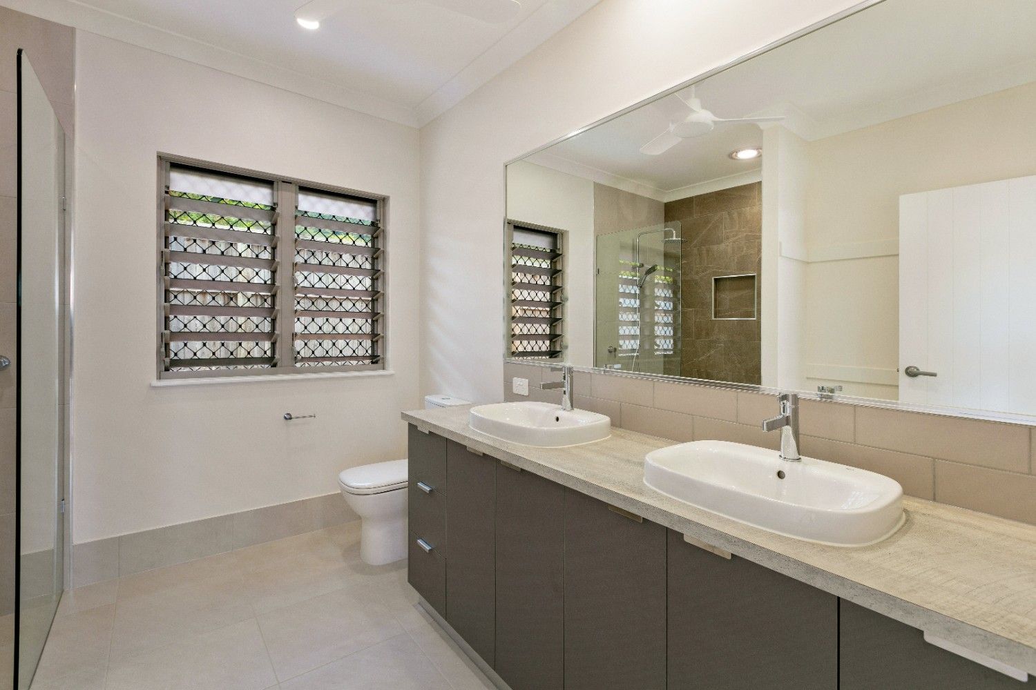 A Bathroom With Two Sinks, a Toilet and a Large Mirror — Ashlee Jones Homes in Gordonvale, QLD