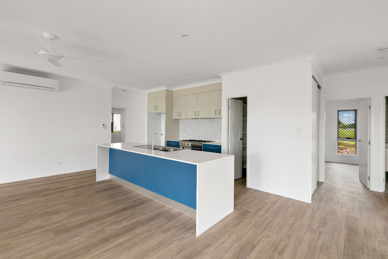 An Empty Kitchen With a Blue Island and White Cabinets — Ashlee Jones Homes in Gordonvale, QLD