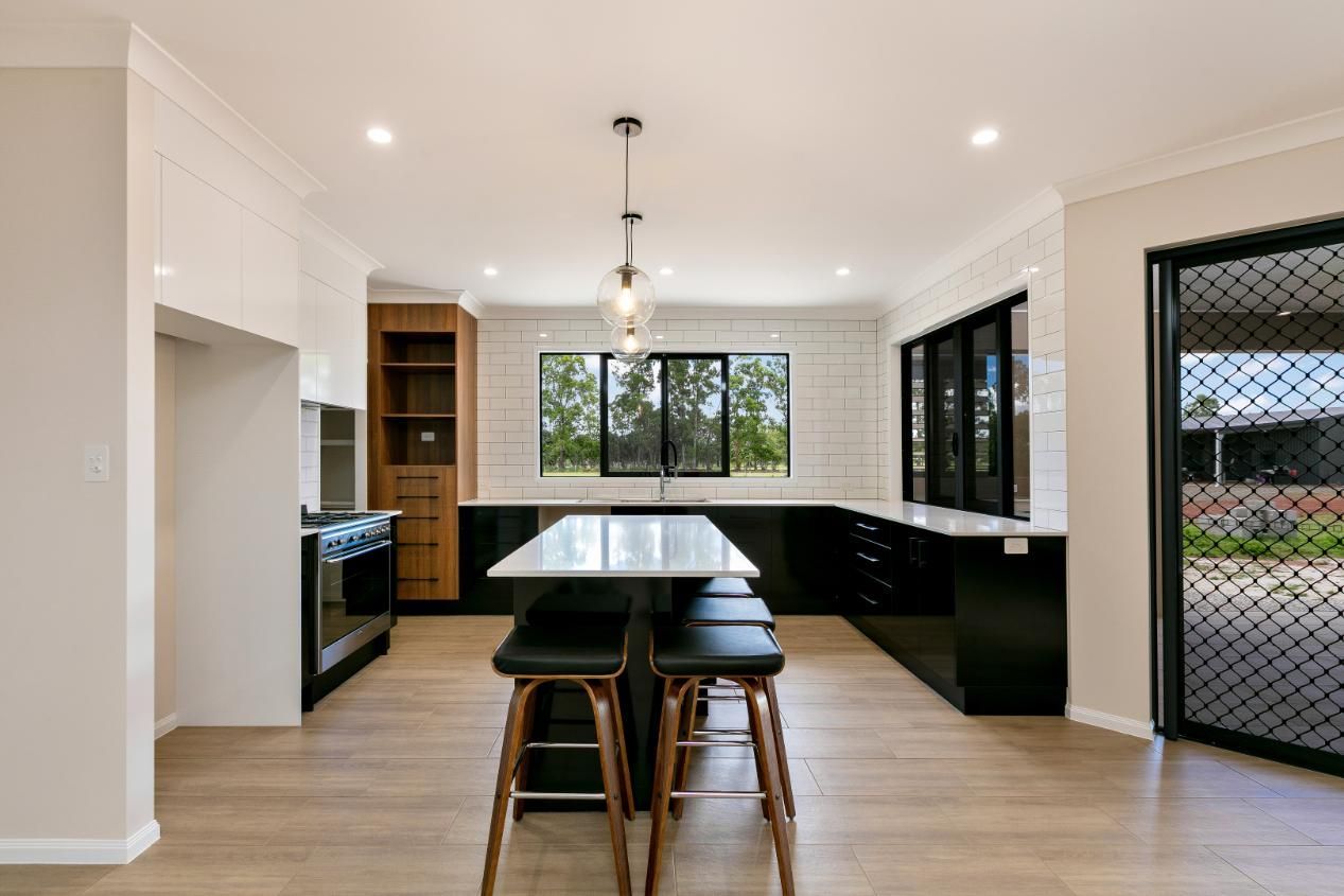 A Kitchen With a Table and Stools in It — Ashlee Jones Homes in Gordonvale, QLD