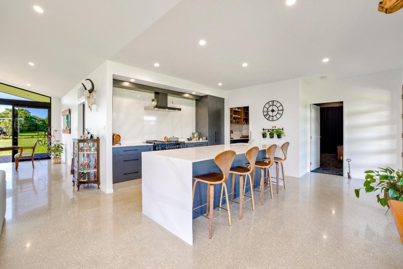 A Kitchen With a Large Island and Stools in a House — Ashlee Jones Homes in Gordonvale, QLD
