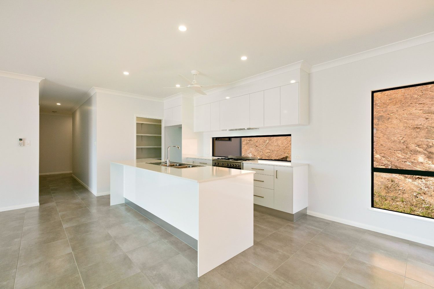 A Kitchen With White Cabinets and a Large Island in the Middle of the Room — Ashlee Jones Homes in Gordonvale, QLD