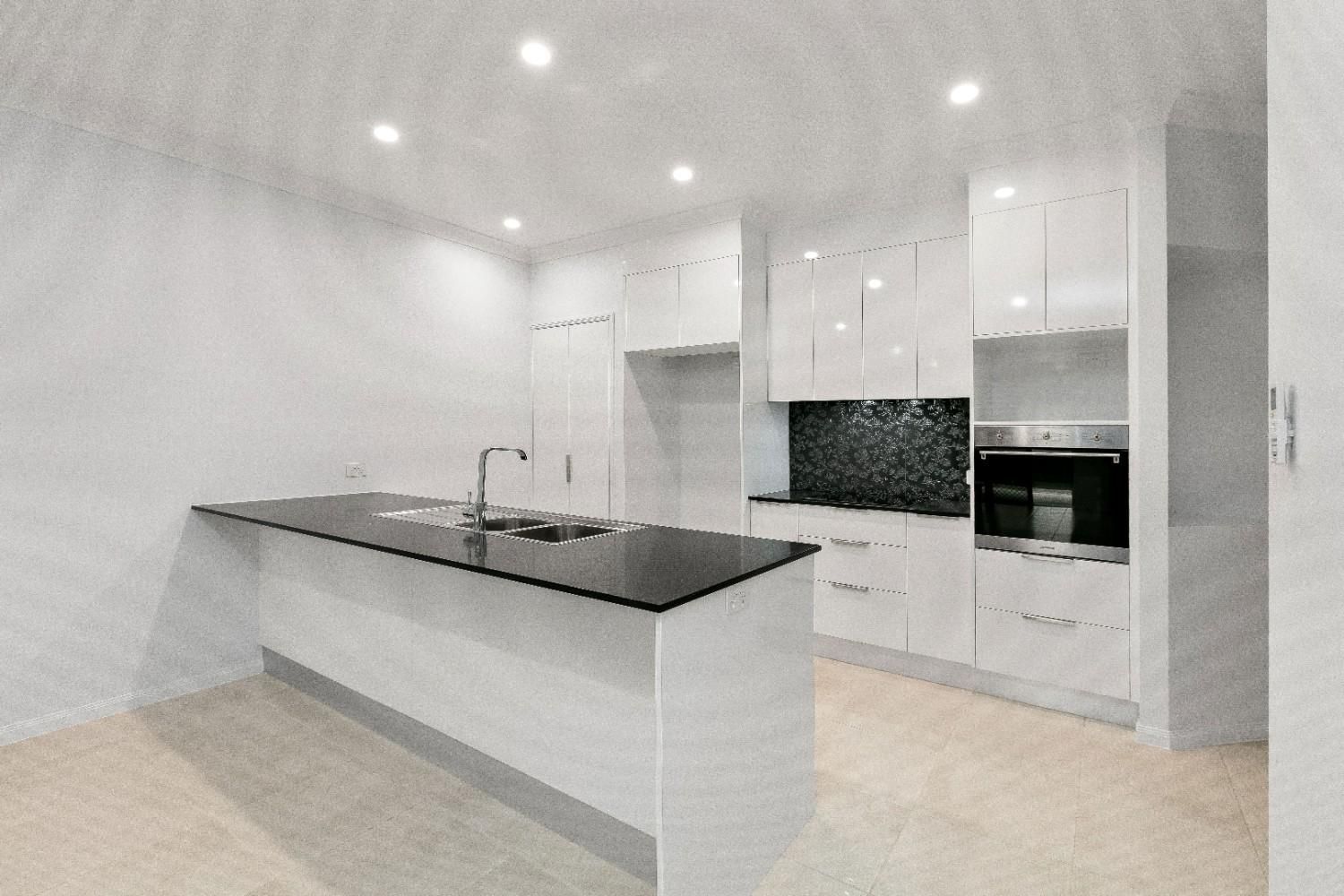 A Kitchen With Cabinets and a Black Counter Top — Ashlee Jones Homes in Gordonvale, QLD