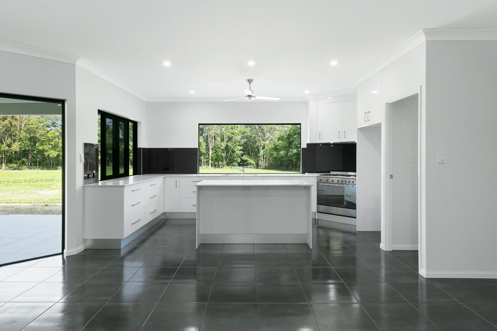 An Empty Kitchen With White Cabinets and Black Tile Floors — Ashlee Jones Homes in Gordonvale, QLD