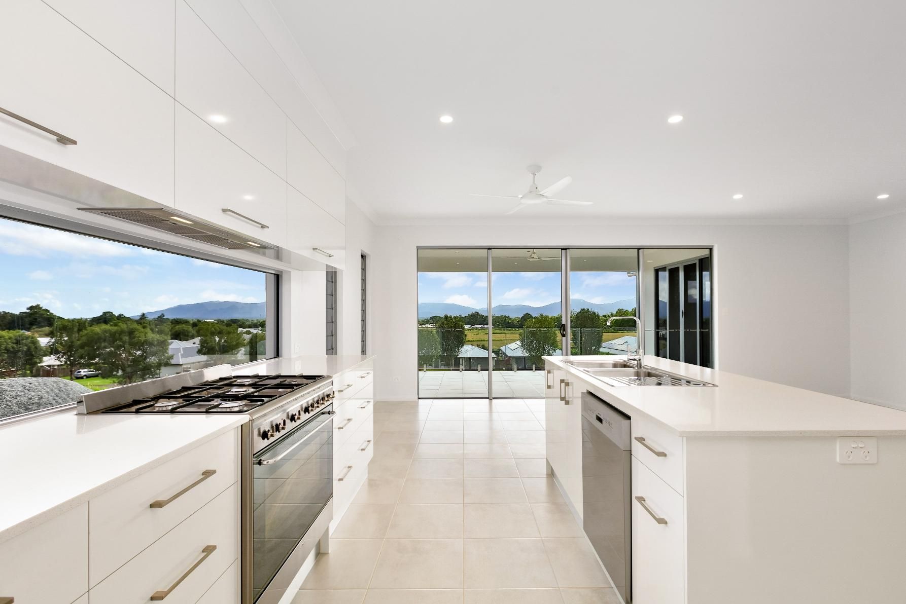 A Kitchen With White Cabinets, a Stove, a Sink, and a Large Window — Ashlee Jones Homes in Gordonvale, QLD
