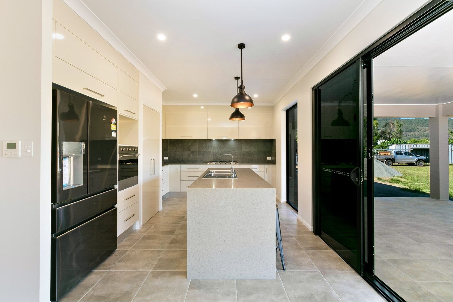 A Kitchen With a Large Island and Sliding Glass Doors — Ashlee Jones Homes in Gordonvale, QLD
